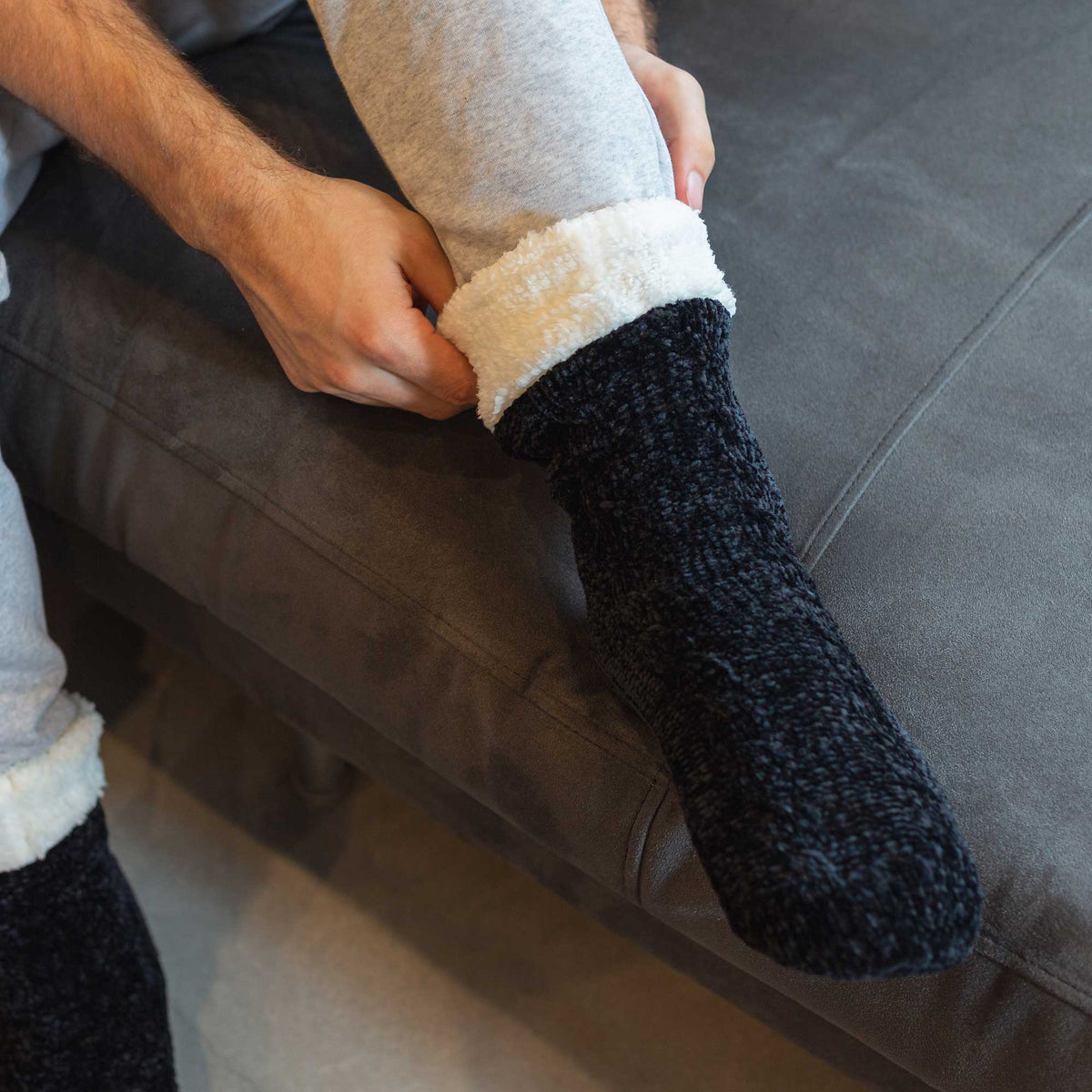 The Foozie™ in Black, pulled on by a man sitting on the sofa