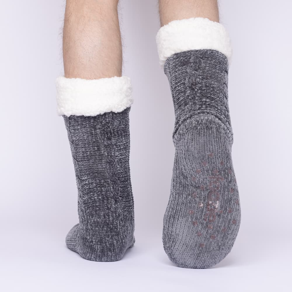 The Foozie™ in Dark Gray, back view worn by a man in Large with one foot raised to show the non-slip grips on the sole