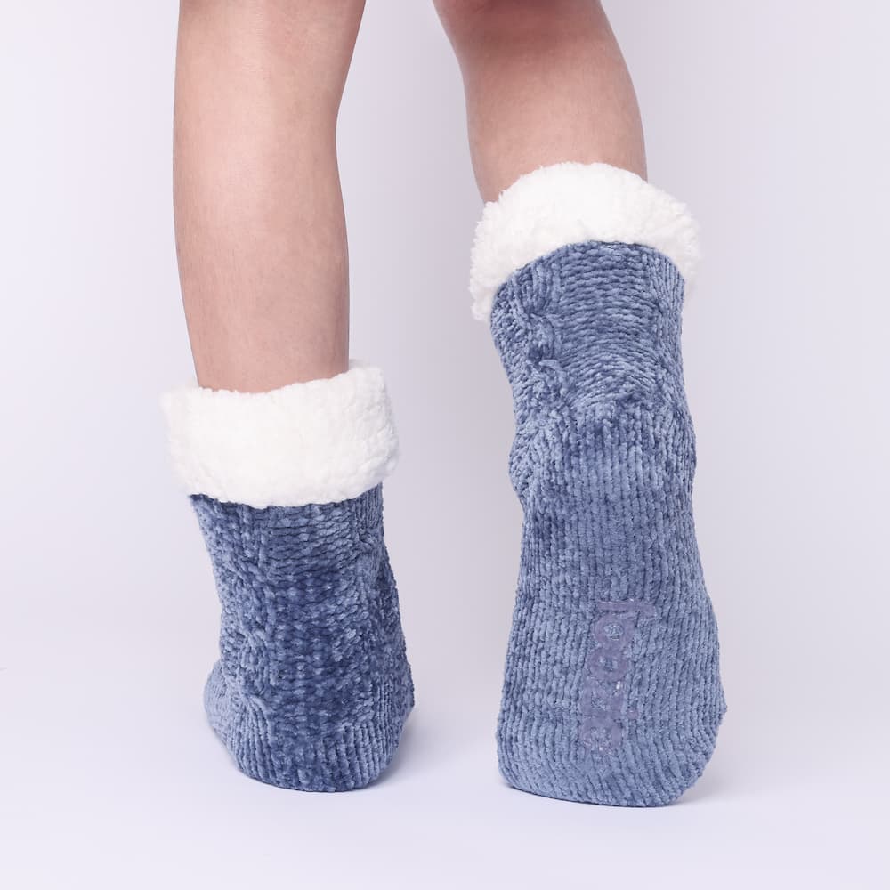 The Foozie™ in Blue, back view worn in Kids/Small with one foot raised to show the non-slip grips on the sole